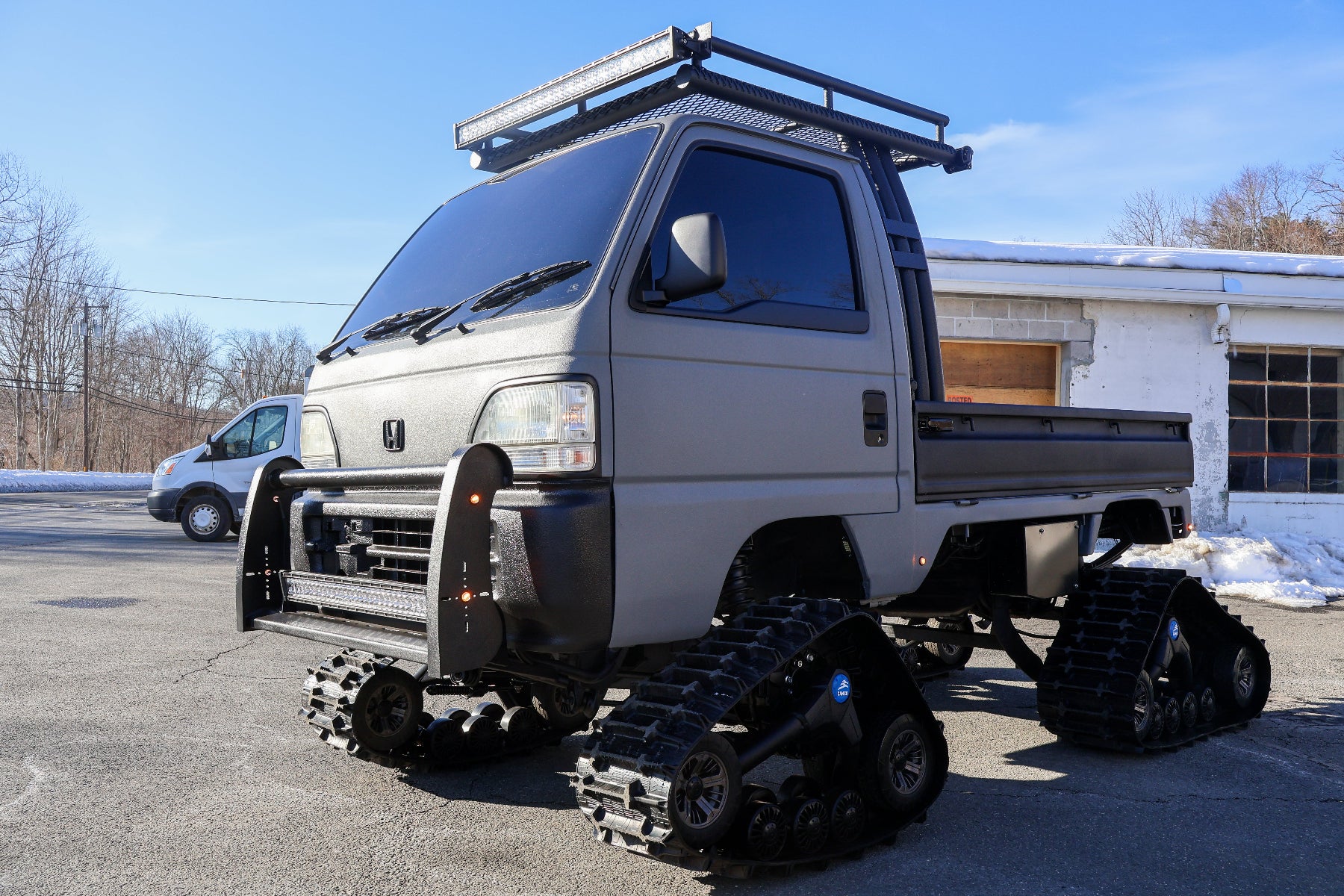 mini truck with a truck body and tracked wheels on a clear day.