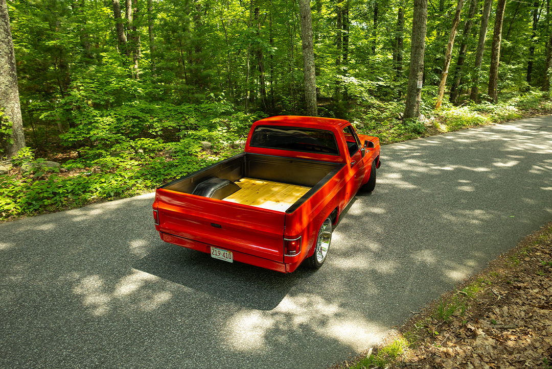 Red C10 pickup on wooded road