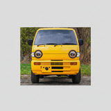 JRB7 custom yellow mini truck canvas on a dirt road with greenery in the background