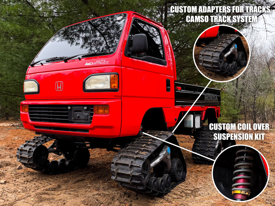 Red Honda truck modified with tracks and suspension system on a forested background