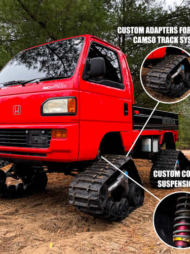 Red Honda truck with custom track system and suspension kit on a dirt road.