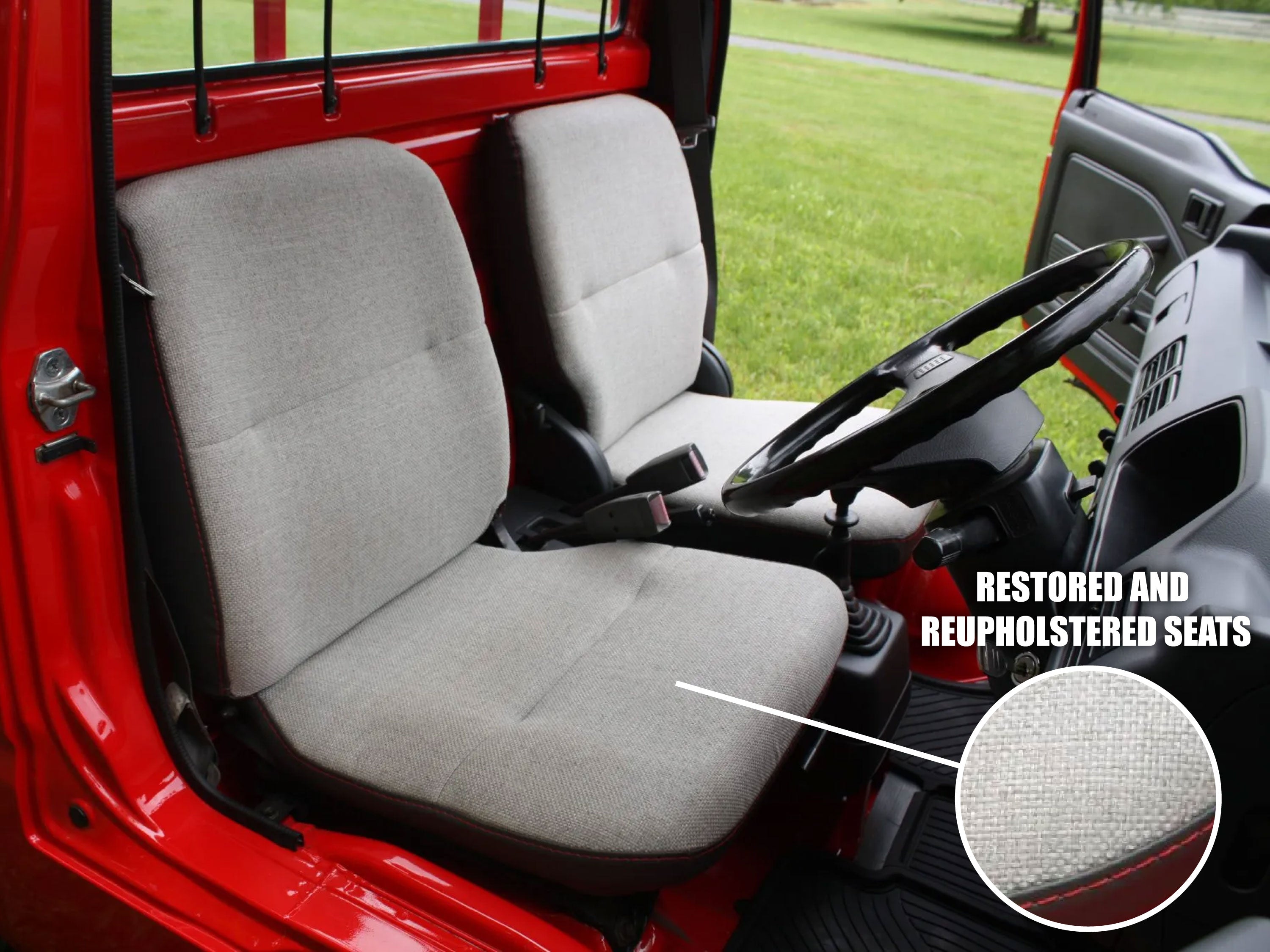Red vehicle interior with gray restored and reupholstered seats and steering wheel.