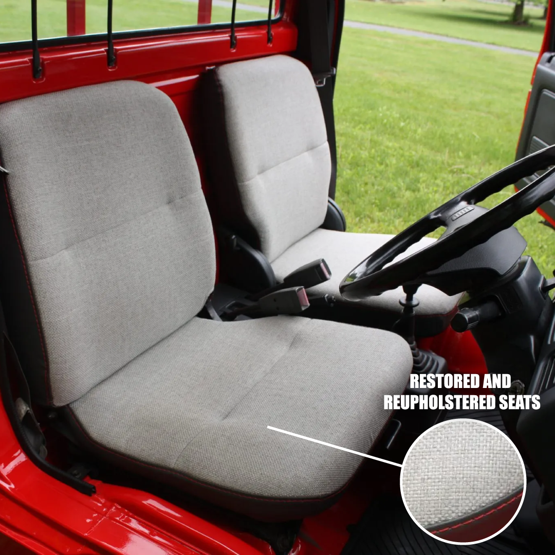 Gray restored and reupholstered seats inside a red vehicle with grass outside.