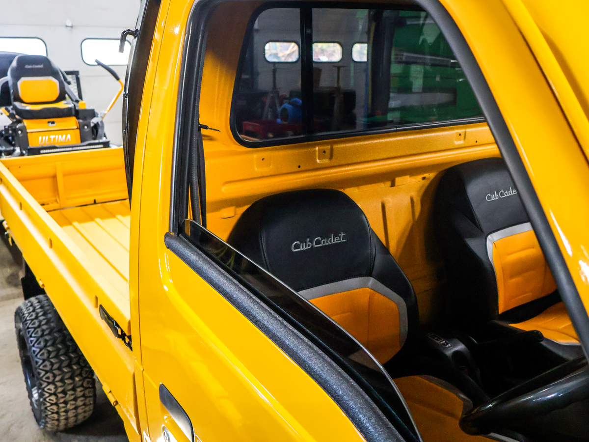 Yellow utility vehicle with black seats and 'Cub Cadet' branding inside.