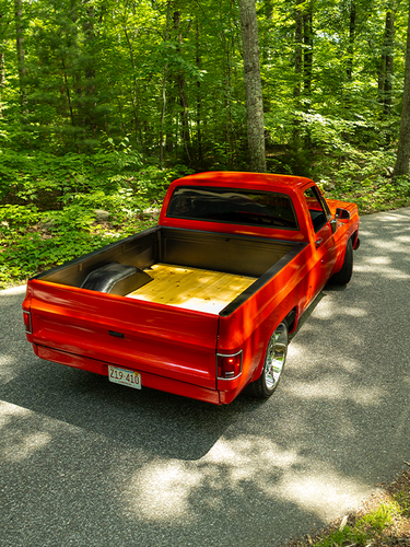 Red C10 pickup on wooded road