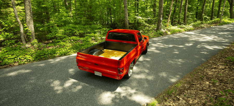 Red C10 pickup on wooded road
